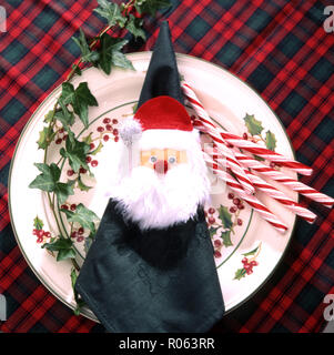 CHRISTMAS PLATE SETTING FEATURING FATHER CHRISTMAS NAPKIN HOLDER, CANDY CANES AND IVY Stock Photo