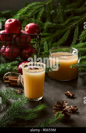 Apple cider cocktail with cardamom and star anise on black table with fir tree branches. Close up. Stock Photo