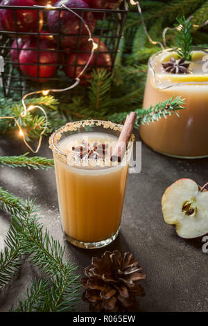 Apple cider cocktail with cardamon and star anise on black table with fir tree branches. Christmas drink. Stock Photo