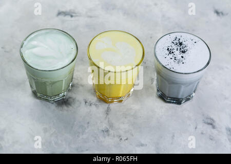 Selection of colorful super lattes matcha tea, tumeric, charcoal on marble background Stock Photo