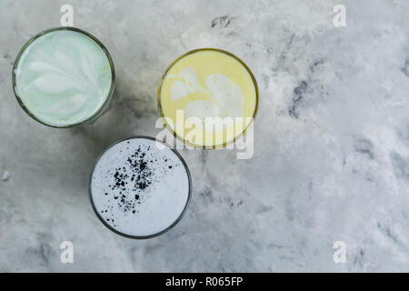 Selection of colorful super lattes matcha tea, tumeric, charcoal on marble background Stock Photo