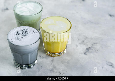 Selection of colorful super lattes matcha tea, tumeric, charcoal on marble background Stock Photo