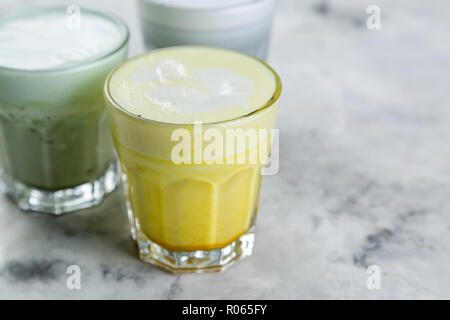 Selection of colorful super lattes matcha tea, tumeric, charcoal on marble background Stock Photo