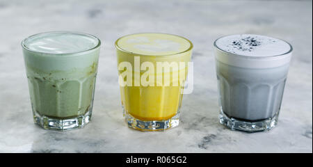 Selection of colorful super lattes matcha tea, tumeric, charcoal on marble background Stock Photo