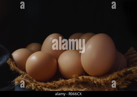 Eggs in a nest on hemp sack, dark corner. Stock Photo
