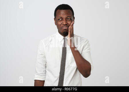 Frustrated young african man touching his cheek suffering from pain. Stock Photo