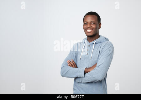 Portrait of happy handsome african man in blue shirt crossing hands and looking at camera Stock Photo