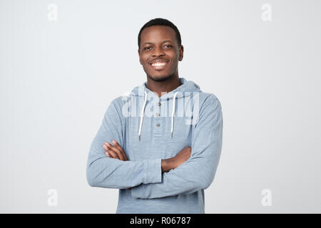 Portrait of happy handsome african man in blue shirt crossing hands and looking at camera Stock Photo
