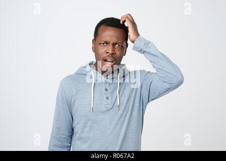 Young african man in blue shirt thinking scratching head on white background Stock Photo