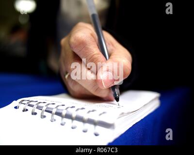 Close up photo of a hand writing on a notebook using a pen Stock Photo