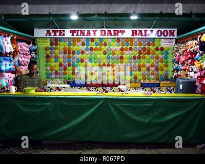 ANTIPOLO CITY, PHILIPPINES - OCTOBER 27, 2018: A worker prepare balloons to be used as targets at his stall in a carnival. Stock Photo