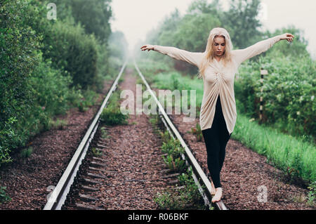 Portrait of young girl walking on rails in motion with hands on opposite directions Stock Photo