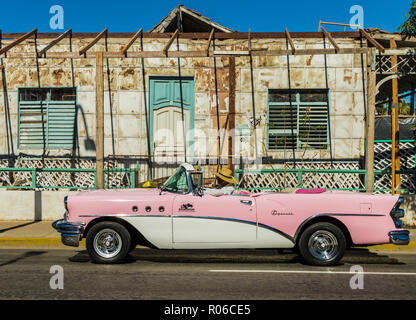 A classic American car driving past an old building in Varadero, Cuba, West Indies, Caribbean, Central America Stock Photo