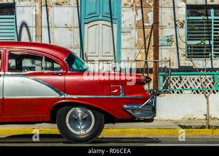 A classic American car driving past an old building in Varadero, Cuba, West Indies, Caribbean, Central America Stock Photo