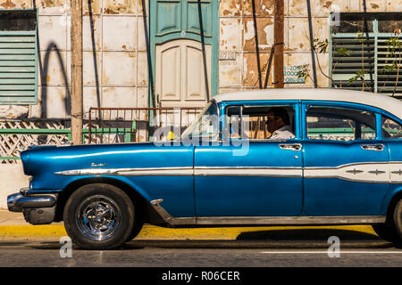 A classic American car driving past an old building in Varadero, Cuba, West Indies, Caribbean, Central America Stock Photo