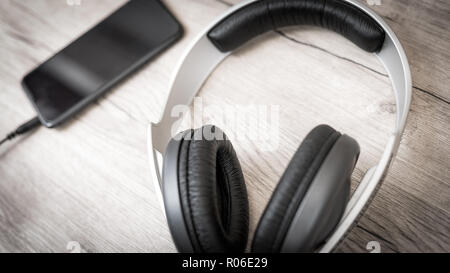 Silver headphones and smart phone on wooden table Stock Photo