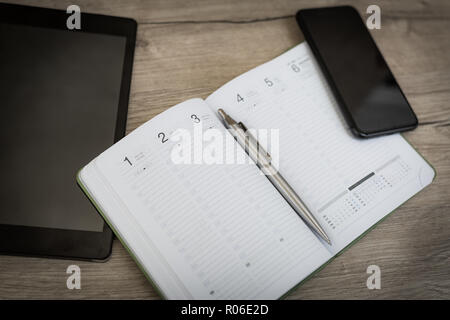 Blank notebook with pen and smartphone on wooden table, business concept Stock Photo