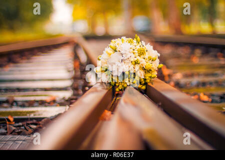 Wedding bouquet lies on railway artistic wedding background, flowers and colorful bokeh background Stock Photo