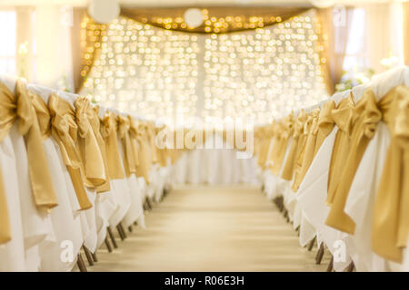 Wedding table that decorated with flower arrangements and candles. Golden lights and white chairs, beautiful celebration of wedding concept Stock Photo