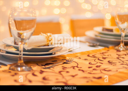 Plate at the wedding table, wine glass and blurred golden bokeh lights. Amazing wedding concept background. Luxury and elegant table setup for wedding Stock Photo