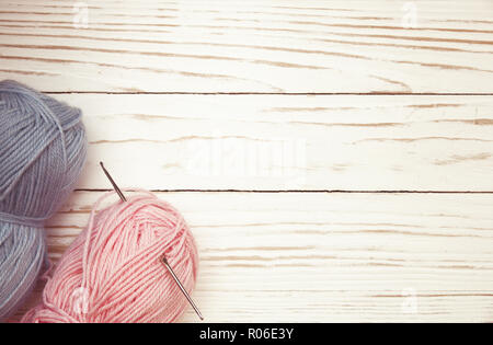 top view of blue and pink wool balls of thread and crochet hook on white wooden knitting background. Stock Photo