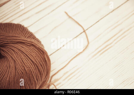 top view of brown woolen tangles of threads on white wooden knitting background. Stock Photo