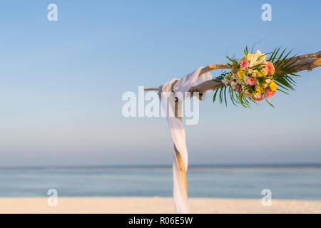 Wedding set up on the beach (vintage colour picture style). Beautiful bridal bouquet of white roses and orchids on a background of the sea. Stock Photo