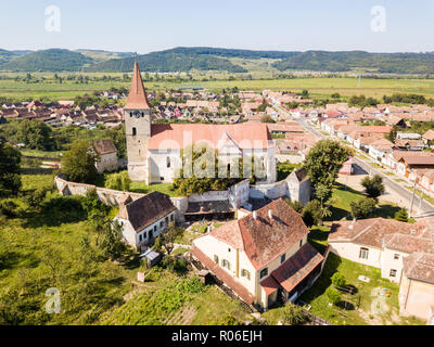 Saros pe Tarnave, fortified church, Transylvania, Romania. Medieval castle on a hill with high spire, walls, red tiled roofs, surrounded by a village. Stock Photo