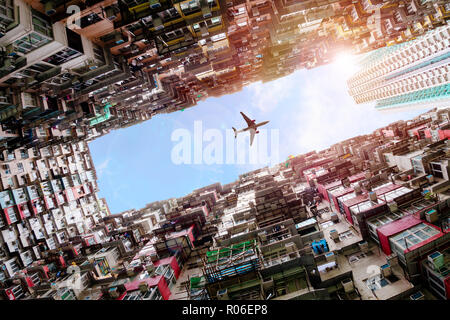 Plane flying dramatically overhead in Hong Kong's old densely residential housing district of Quarry Bay with deliberate lens flare.