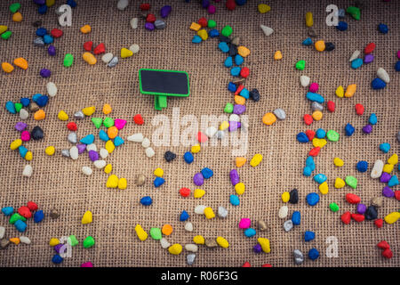 Little noticeboard amid Colorful pebbles spread on canvas Stock Photo