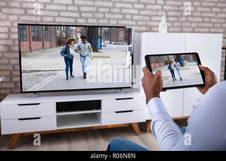 Man Connecting Television Channel Through Wireless On Digital Tablet At Home Stock Photo