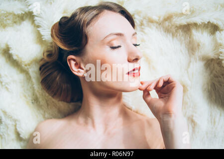 Beautiful portrait of young girl in retro style on fur, closed eyes Stock Photo