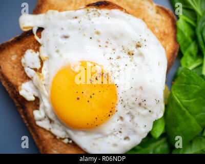 Fried eggs on toast and spinach close up from above on blue plate Stock Photo