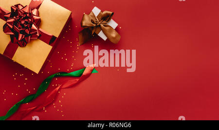 Various gift boxes with stars and colorful ribbons with copy space. Different sized gift boxes tied with ribbon on red background. Stock Photo