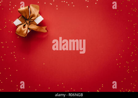 Small gift box with stars on red background. Top view of christmas gift with stars, flat lay on red background. Stock Photo