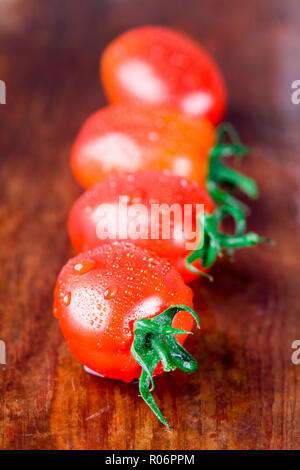 macro images of four wet tomatoes closeup on wooden table Stock Photo
