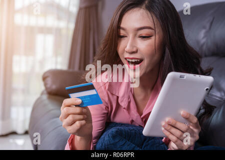 surprised woman using laptop computer for online shopping with credit card in the living room Stock Photo