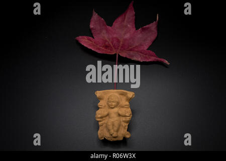 Baby Jesus Christ in the manger on a dry leaf isolated on black background. Christmas Nativity Scene figure. Stock Photo