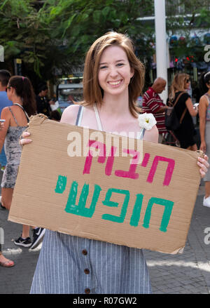 A smiling young lady with a Hebrew sign saying 'Free Hug' at the Carmel Market in Tel aviv, Israel. Stock Photo