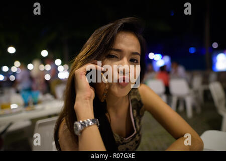 Close up of young beautiful Asian woman talking on mobile phone  Stock Photo