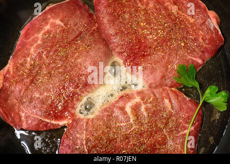 Red steak fried in a frying pan close up. Cooking of the meat top view Stock Photo