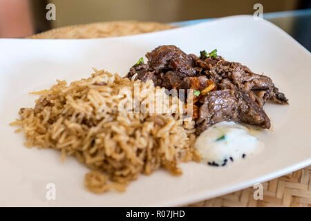 Shuwa - a traditional Omani dish where meat is marinated in spices, wrapped in palm or banana leaves and then cooked underground - served with rice Stock Photo