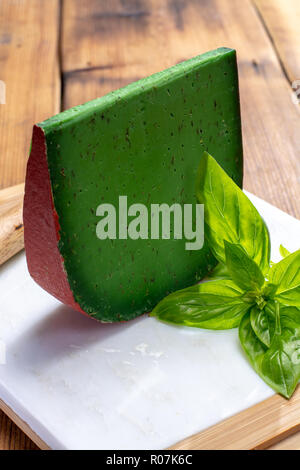 Cheese collection, piece of Dutch green pesto hard cheese with fresh basil close up Stock Photo