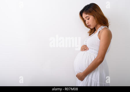 Profile view of young Asian pregnant woman looking at her stomac Stock Photo