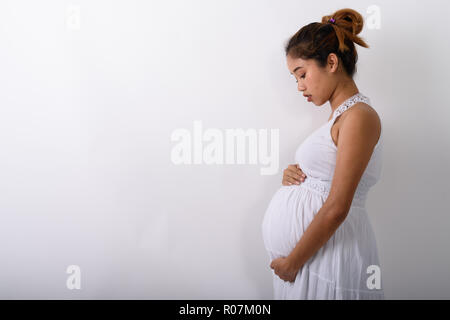 Profile view of young Asian pregnant woman holding her stomach a Stock Photo