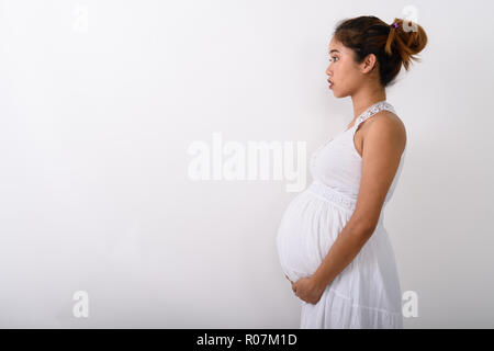 Profile view of young Asian pregnant woman holding the baby in h Stock Photo