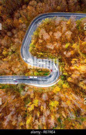 Aerial view of a winding road with trucks in a frozy winter sunny day ...