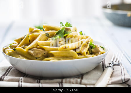 Pasta pene with chicken pieces mushrooms parmesan cheese sauce and herb decoration. Pene con pollo - Italian or medierranean cuisine.