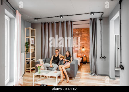 Modern living room with young lovely couple on the couch at their apartment Stock Photo