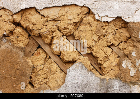 A fragment of an old dilapidated mud walls. Wooden slats are used as fitting Stock Photo